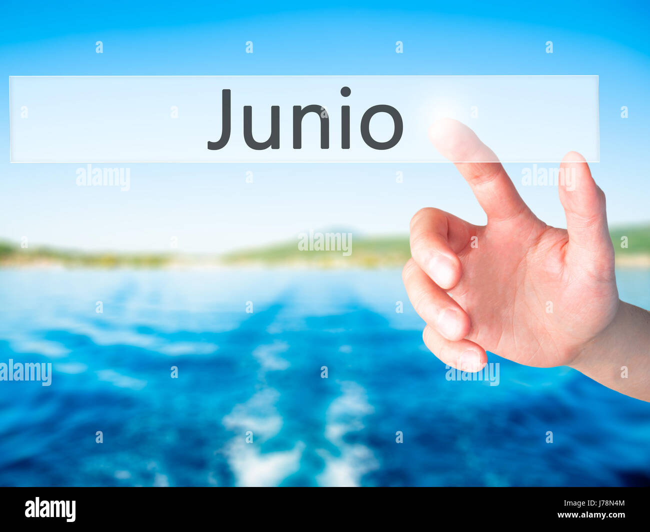 Junio (June in Spanish) Hand pressing a button on blurred background