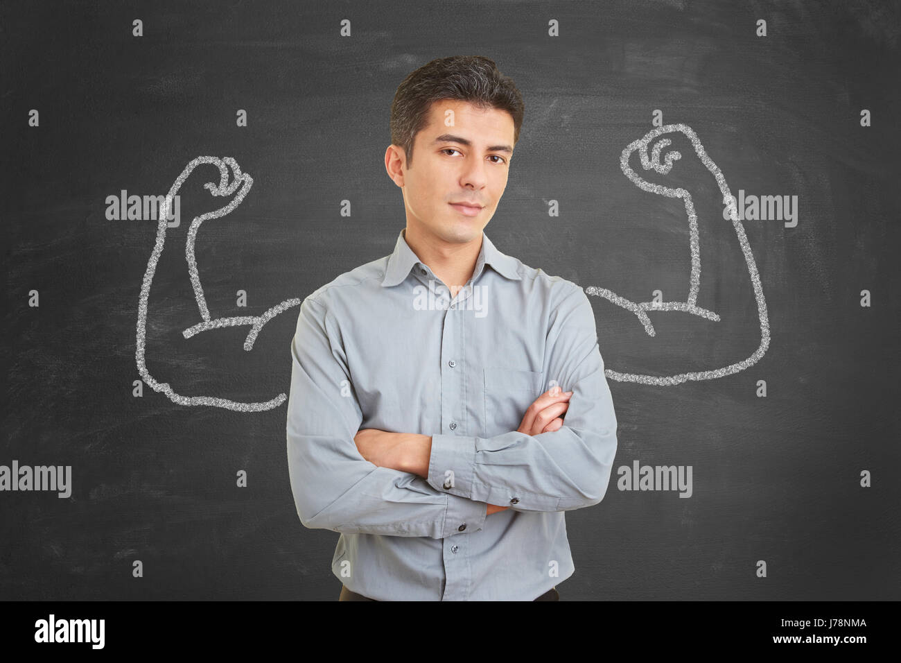 Strong and self confident businessman with chalk muscles on blackboard behind him Stock Photo