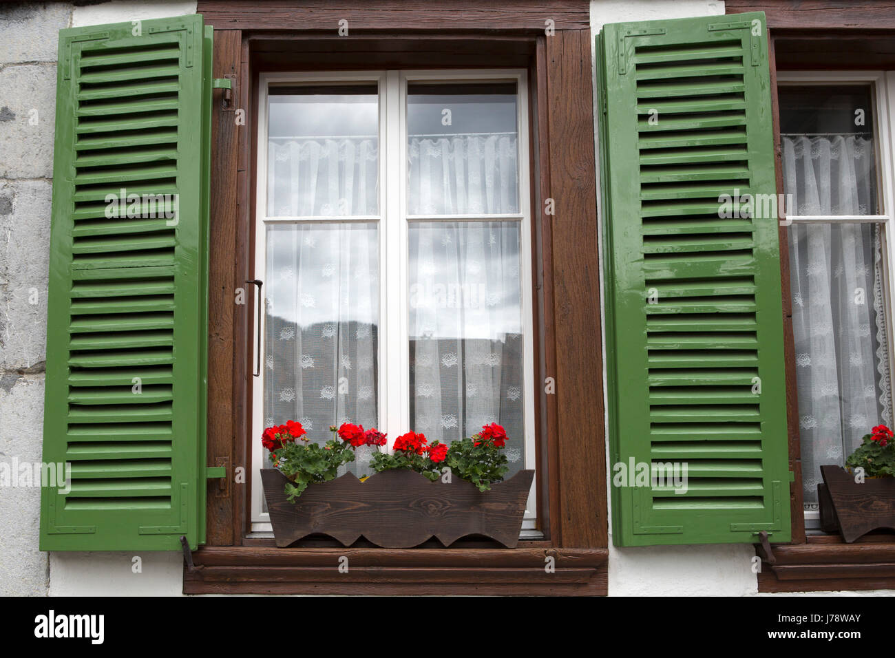Green shutters at Unterssen in Switzerland. The window has a flower box. Stock Photo