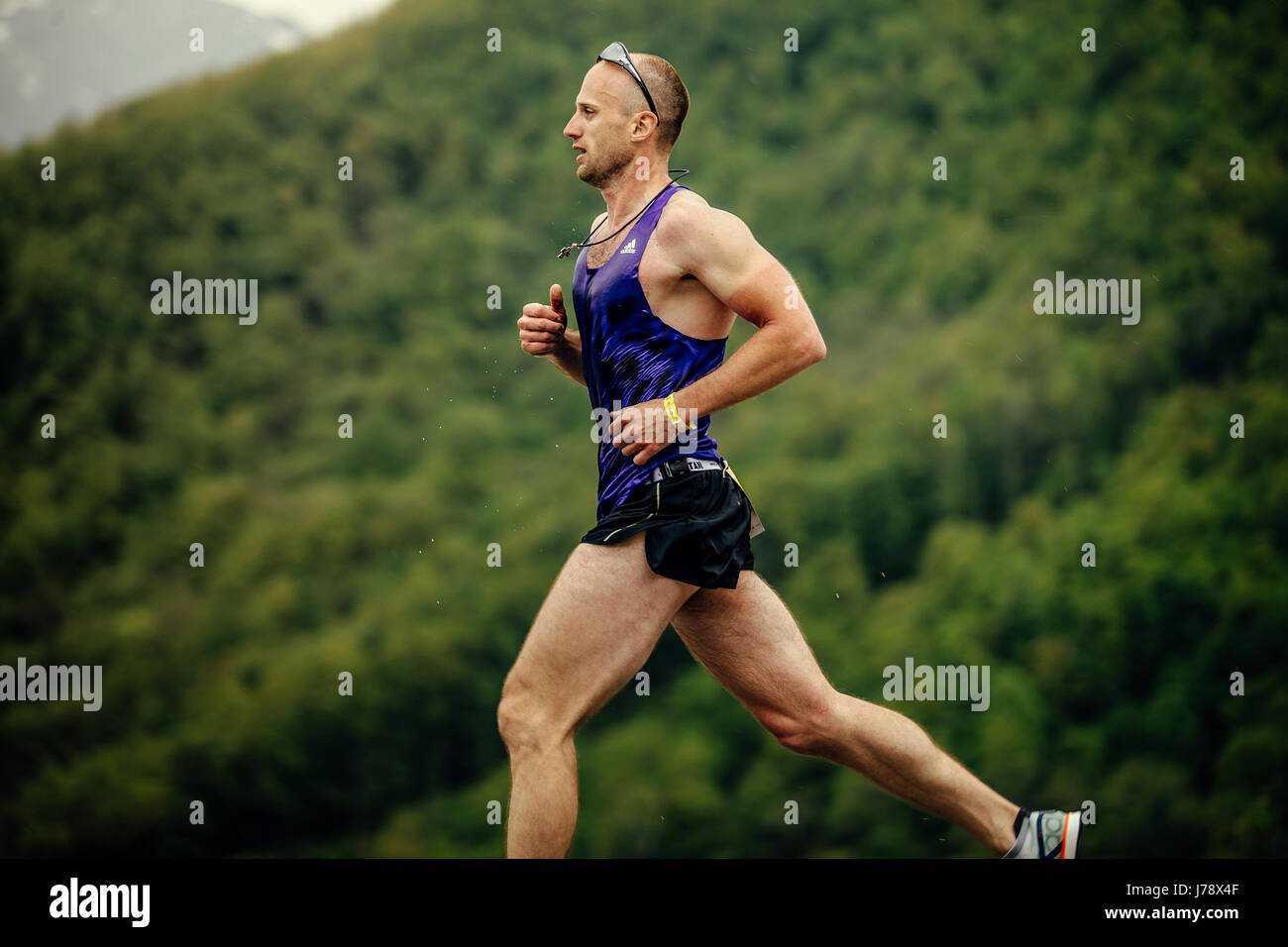 young male athlete runner running background green trees in race Spring mountain marathon Stock Photo