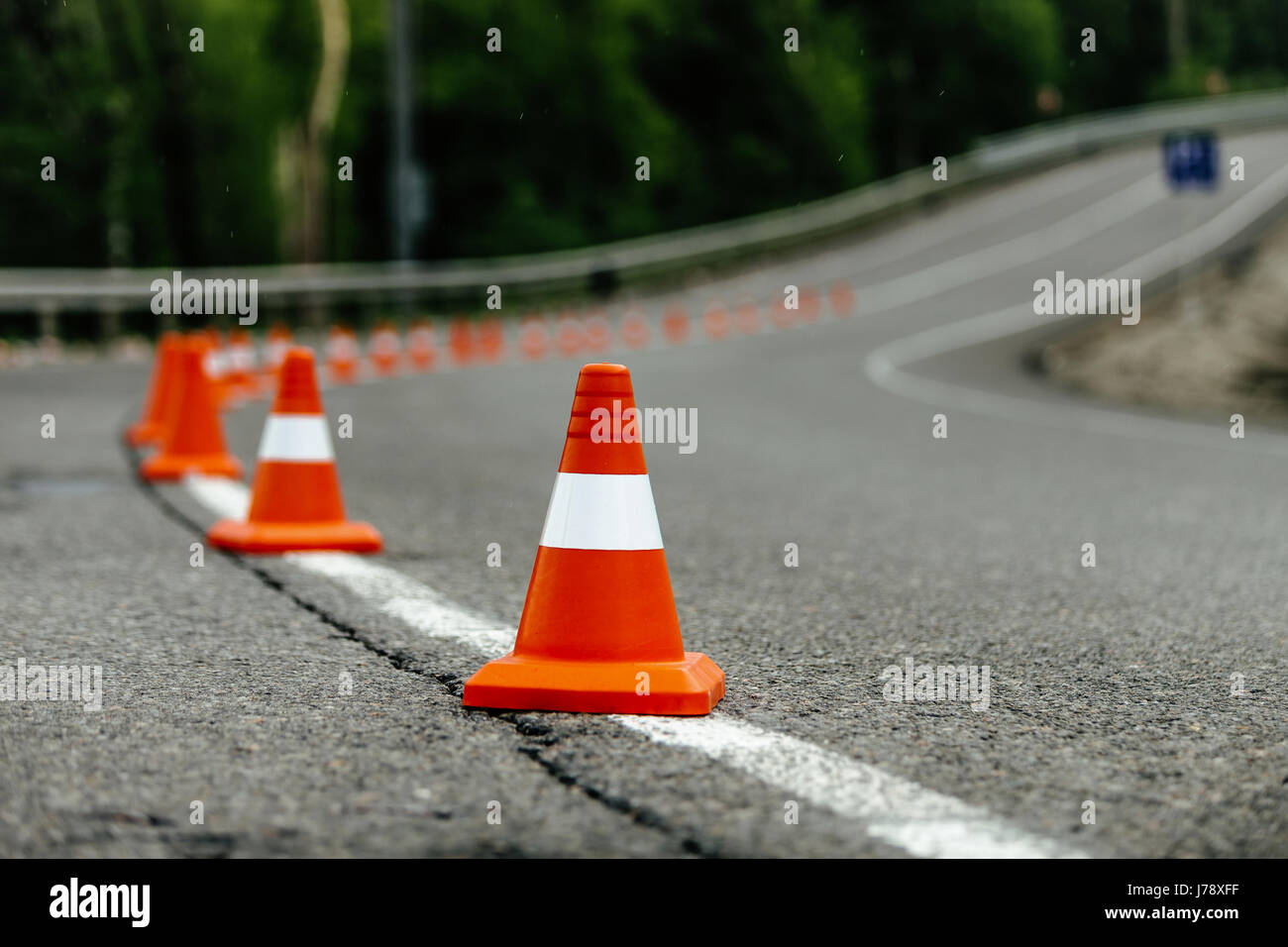 bright orange traffic cones on dark asphalt serpentine mountain roads Stock Photo