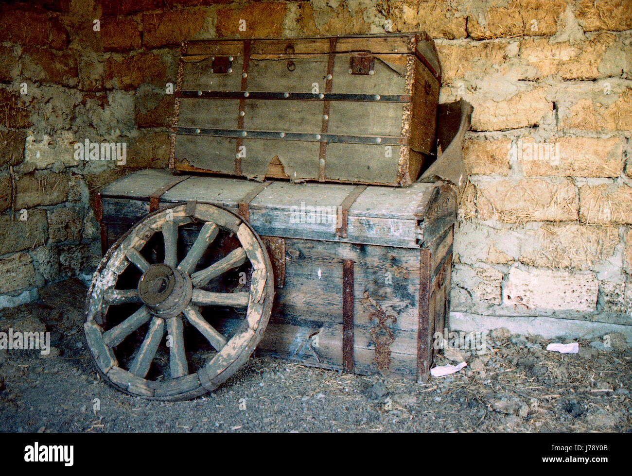 Old wooden chests stand one on one and the wheel is on them Stock Photo