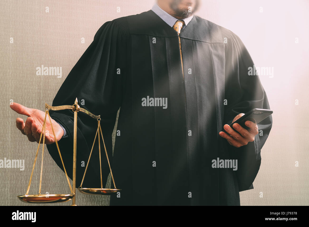 justice and law concept.Male judge in a courtroom with the balance scale and using smart phone Stock Photo