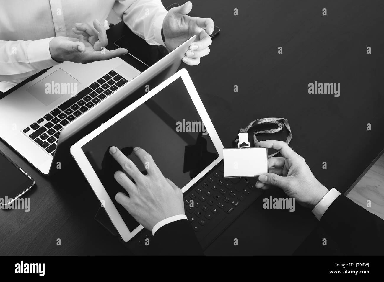 co working team meeting concept,businessman using smart phone and digital tablet and laptop computer and name tag in modern office,black and white Stock Photo