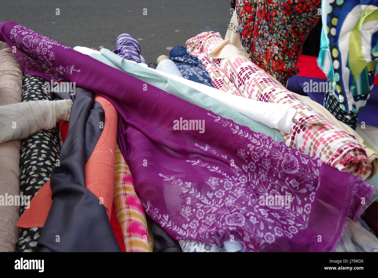 Rolls of colourful headscarf and sari material for sale on a fabric stall at Chalton Street Market in London UK Stock Photo