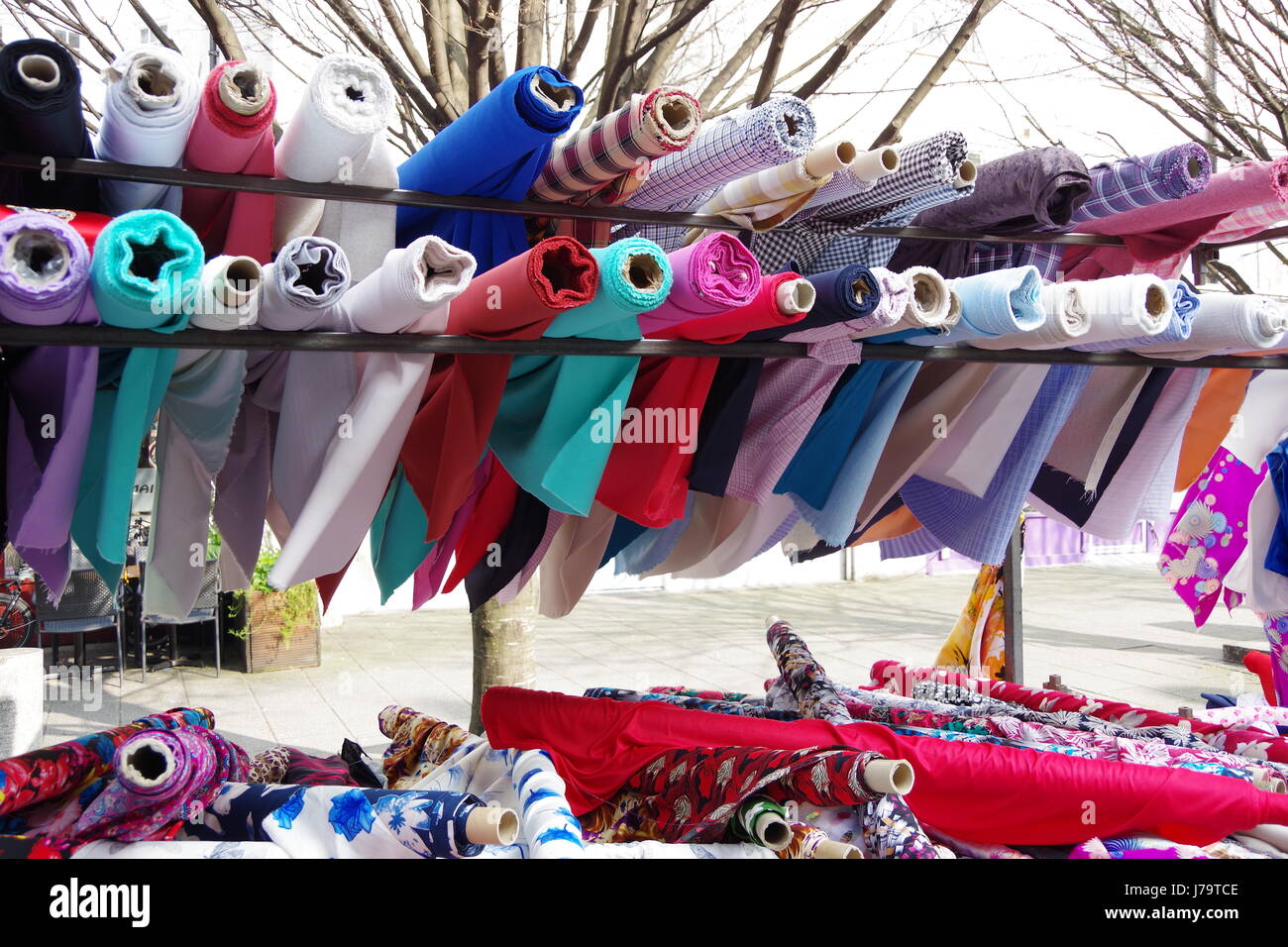 Rolls of colourful headscarf and sari material for sale on a fabric stall at Chalton Street Market in London UK Stock Photo