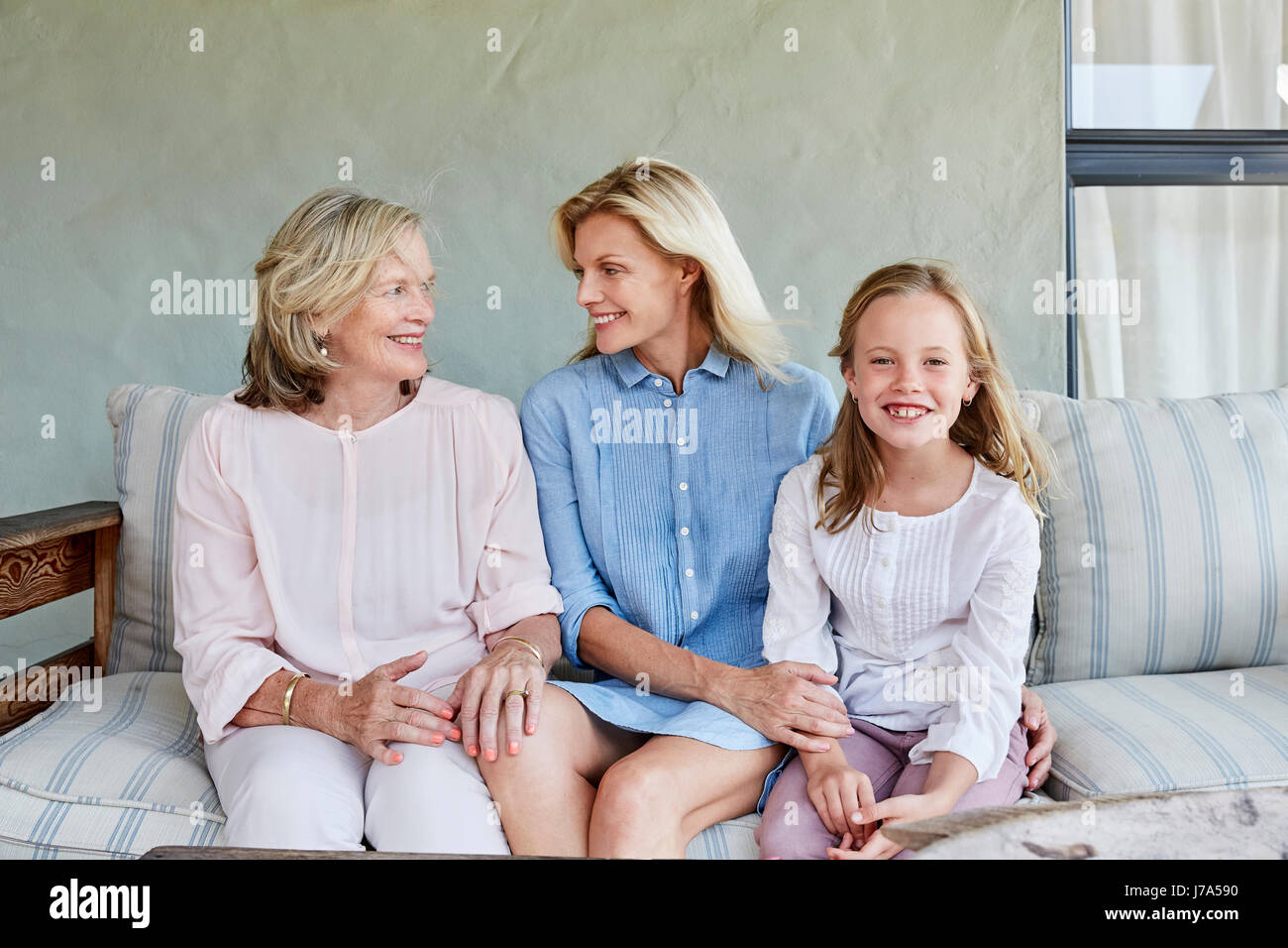 Little girl sitting together with mother and grandmother on terrace ...