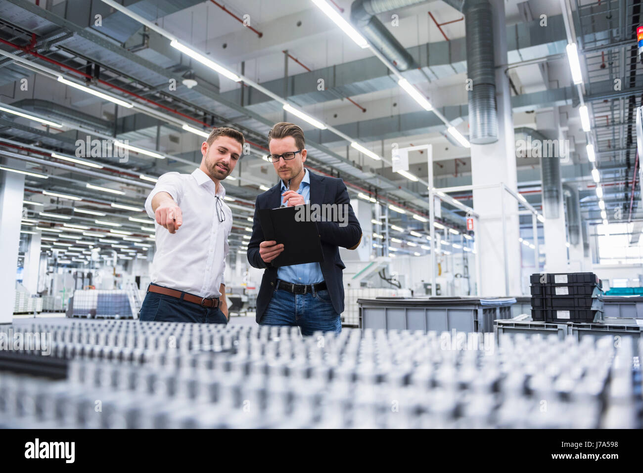 Two men talking in factory shop floor Stock Photo - Alamy