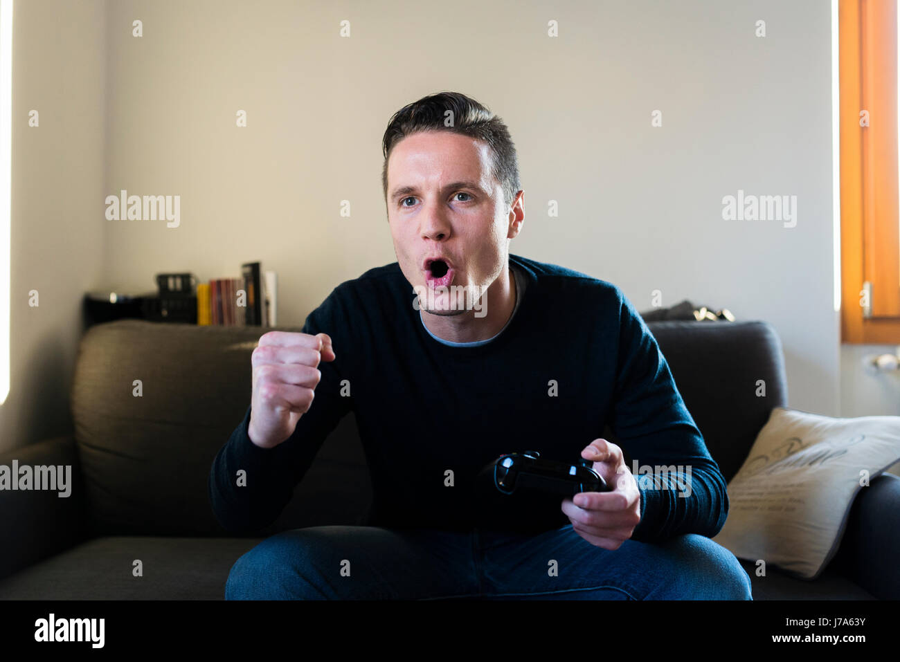 Portrait of screaming man sitting on the couch with games console Stock ...