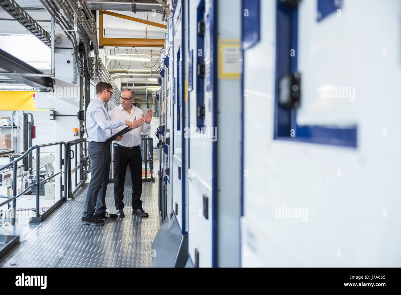 Two men talking in factory shop floor Stock Photo - Alamy