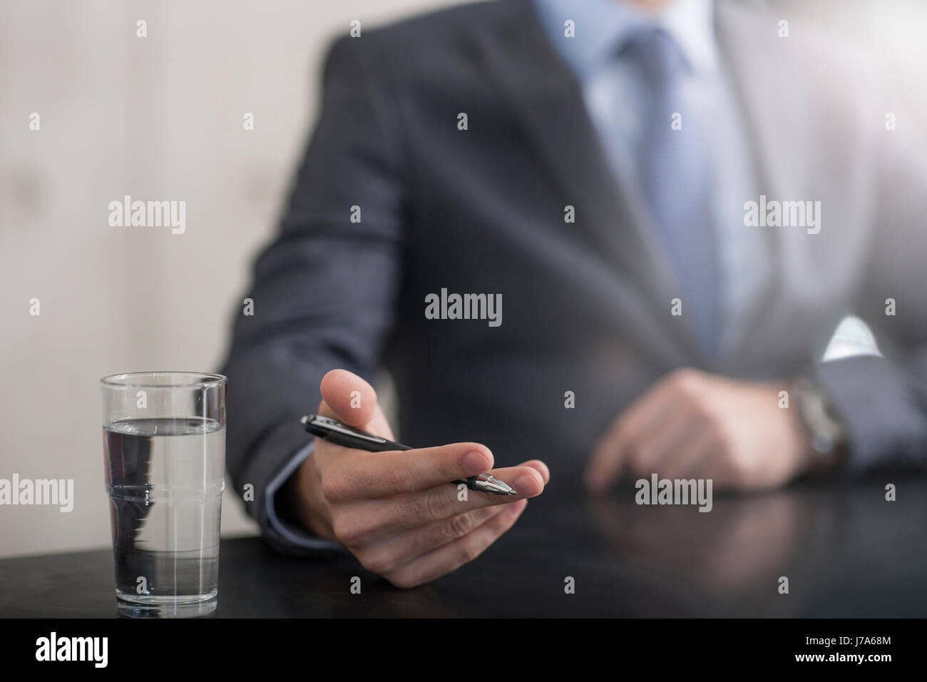 Businessman holding pen next to glass of water Stock Photo - Alamy