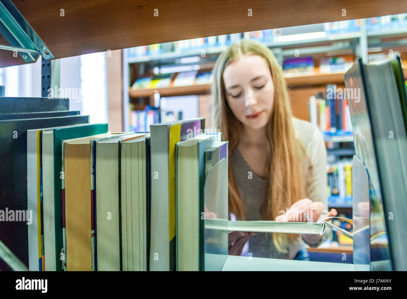 Teenage girl behind bookshelf in a public library Stock Photo - Alamy