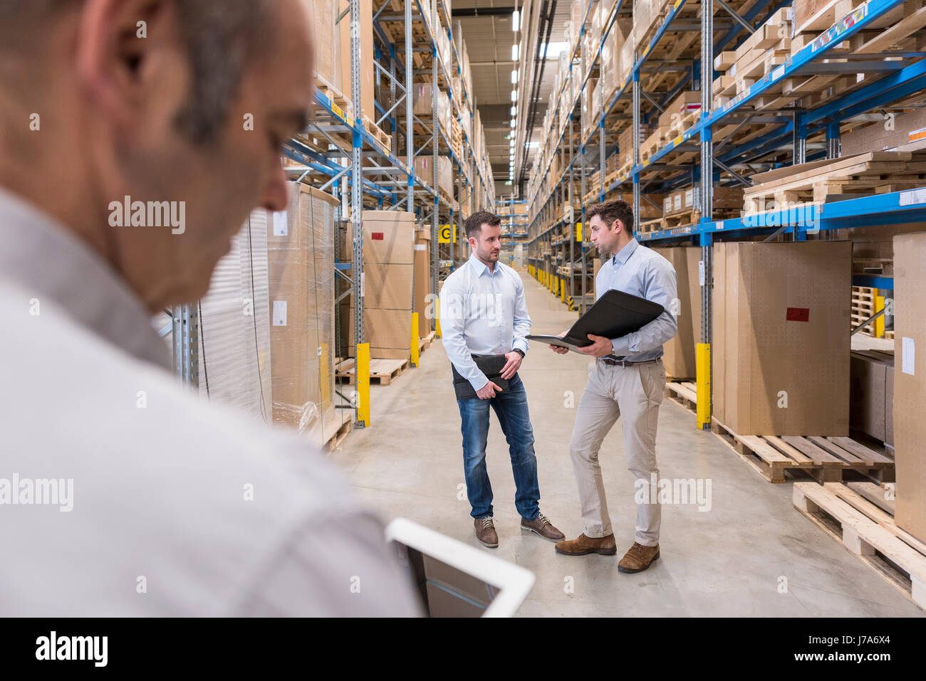 Two men with folder talking in factory warehouse Stock Photo - Alamy