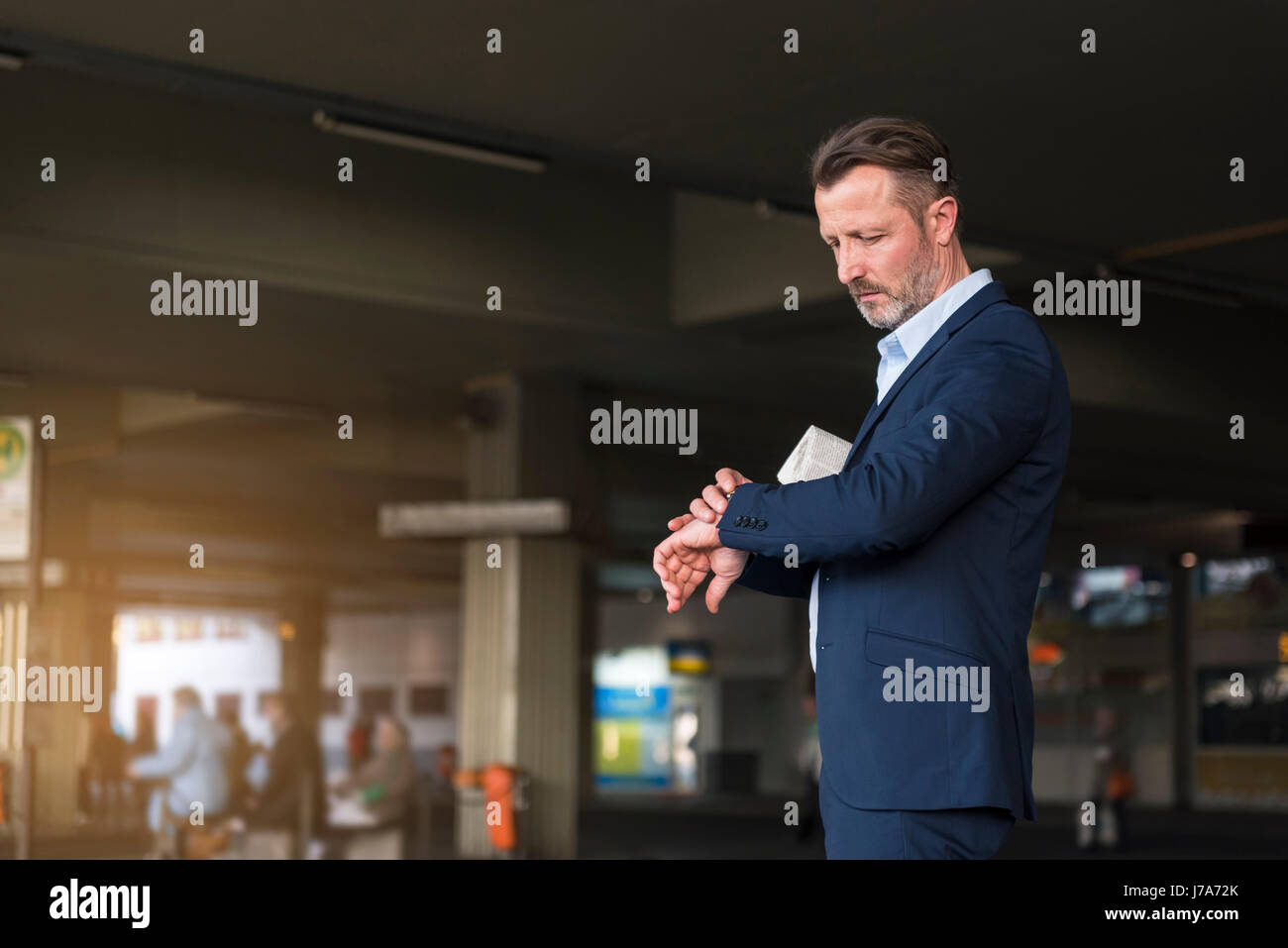 Businessman waiting at bus terminal checking the time Stock Photo