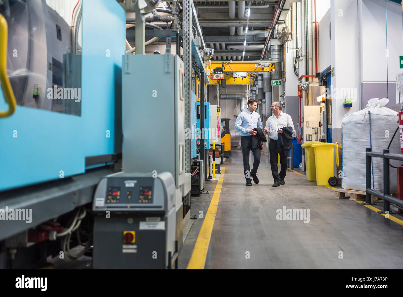 Two men walking and talking in factory shop floor Stock Photo - Alamy