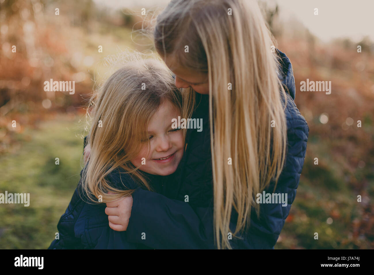 Two cute blond sisters cuddling outdoors Stock Photo