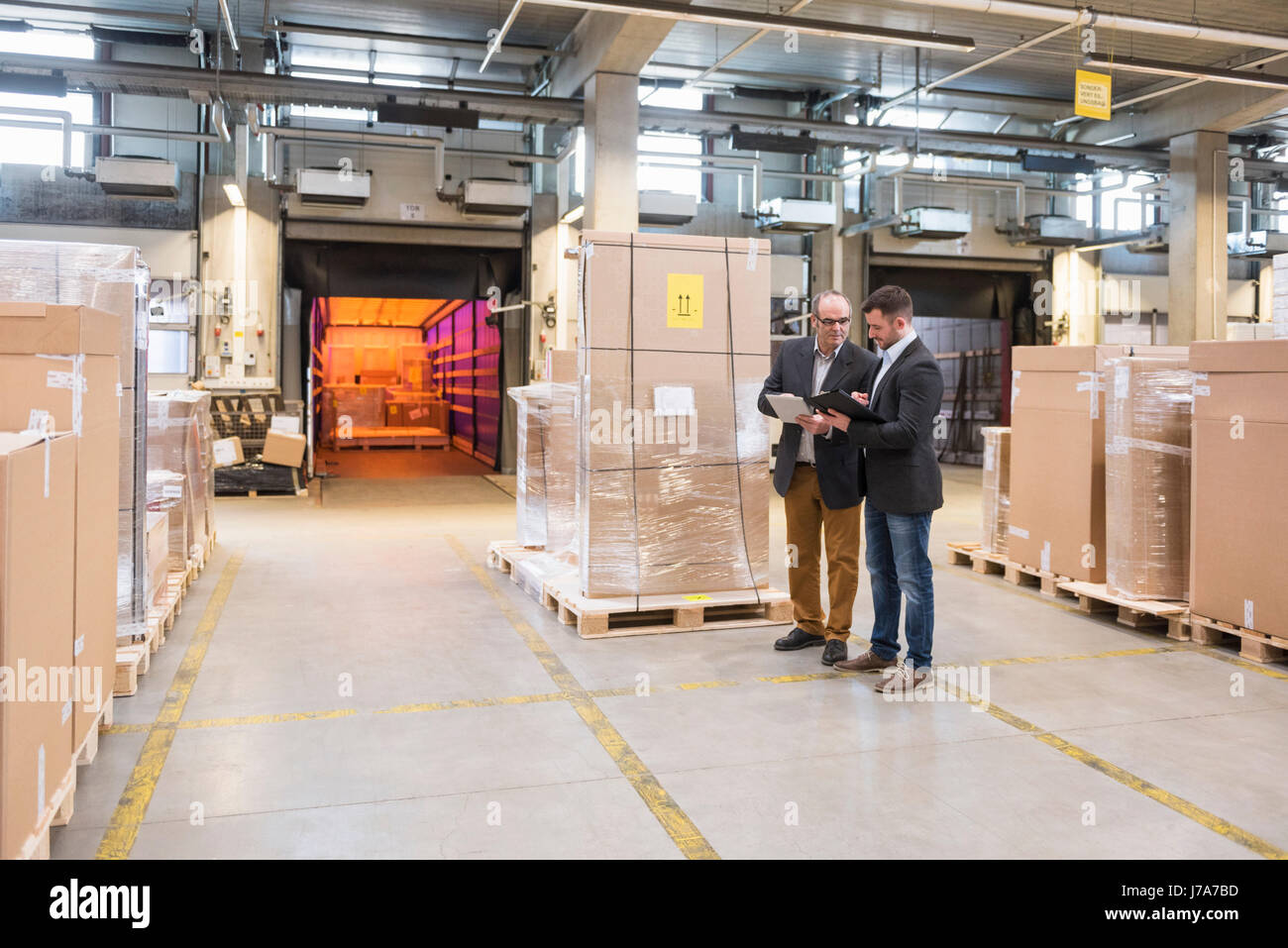 Two men talking in factory warehouse Stock Photo - Alamy