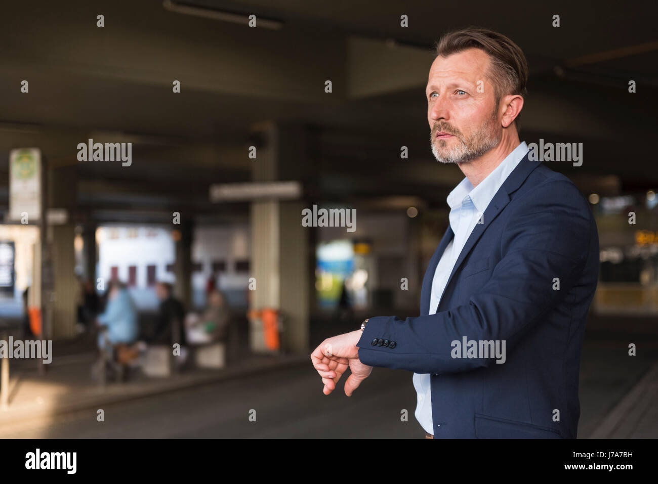 Businessman waiting at bus terminal checking the time Stock Photo