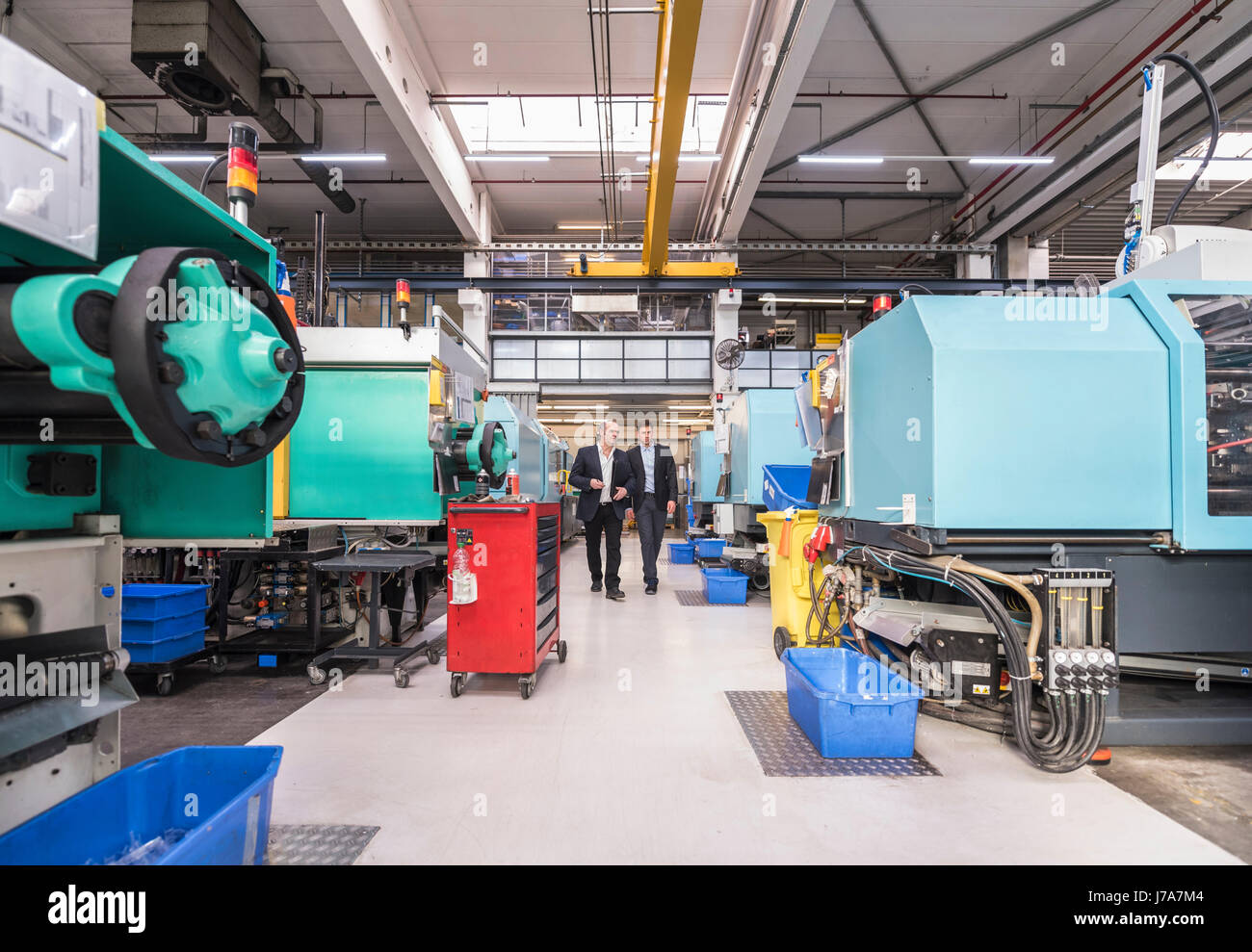 Two men walking and talking in factory shop floor Stock Photo - Alamy
