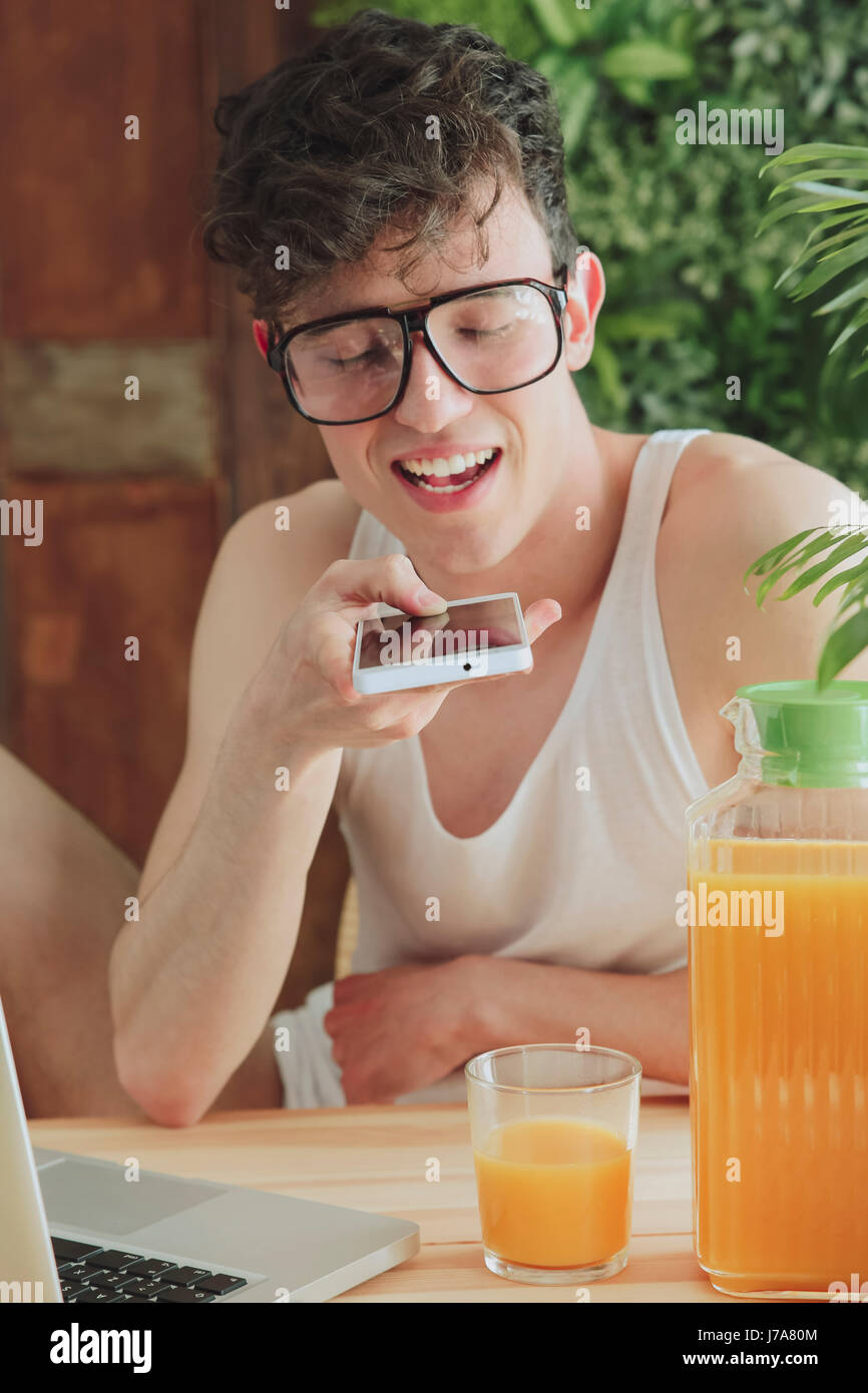 Young man sending voice message with smartphone at home Stock Photo