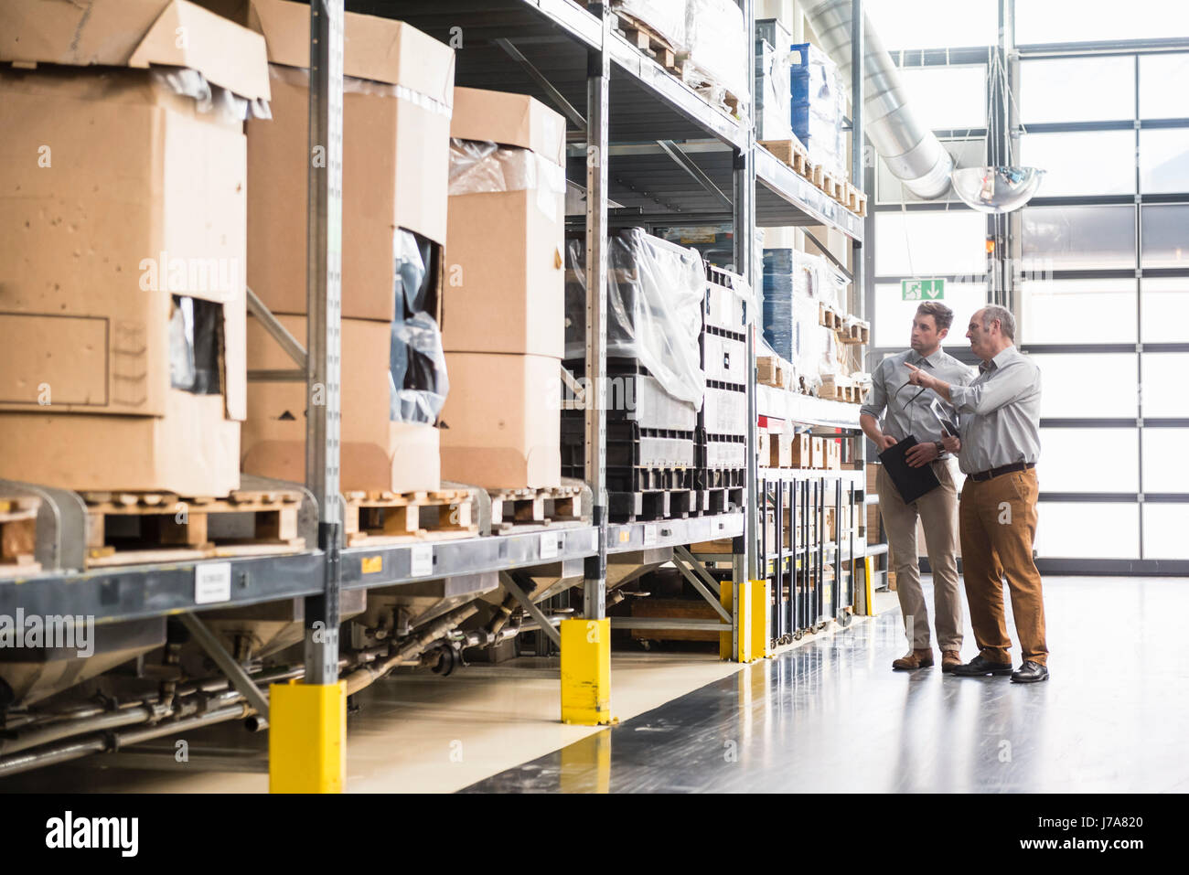 Two men talking in factory warehouse Stock Photo - Alamy