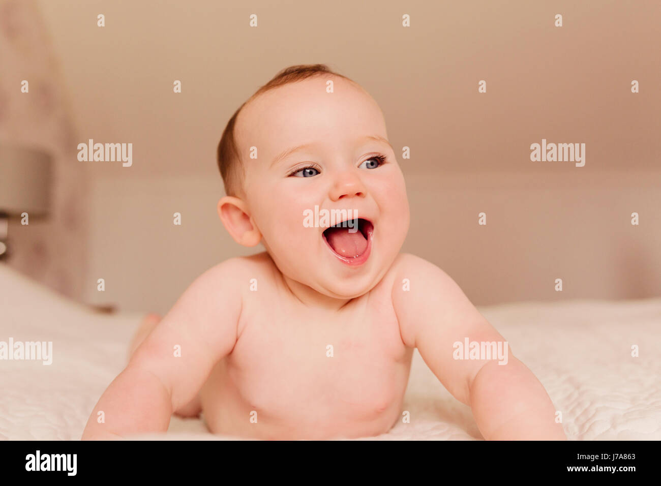 Portrait of laughing baby girl on bed Stock Photo