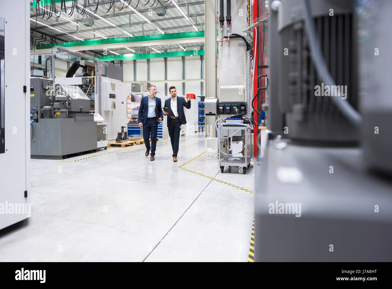 Two men walking and talking in factory shop floor Stock Photo - Alamy