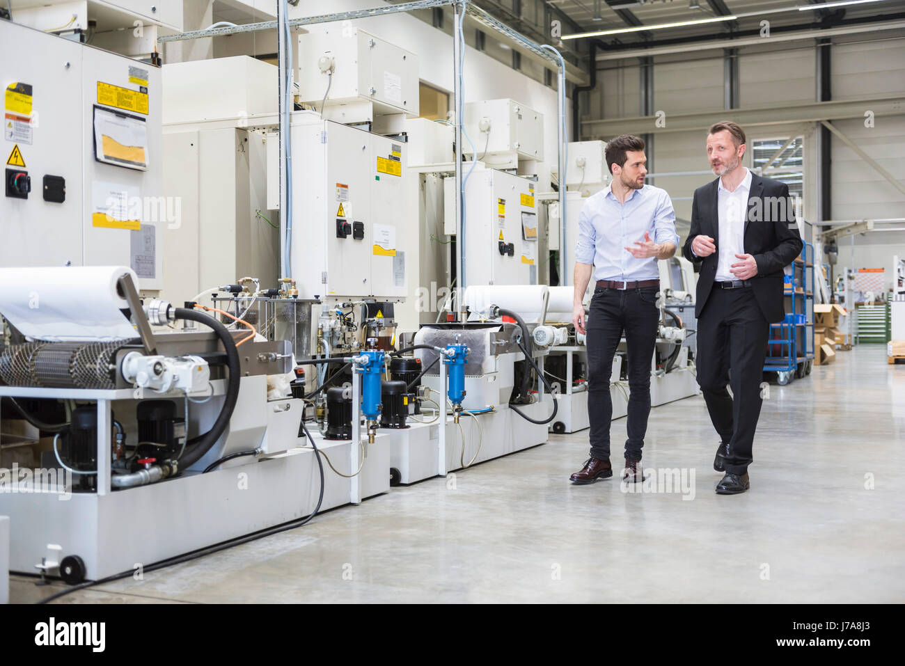 Two men walking and talking in factory shop floor Stock Photo - Alamy