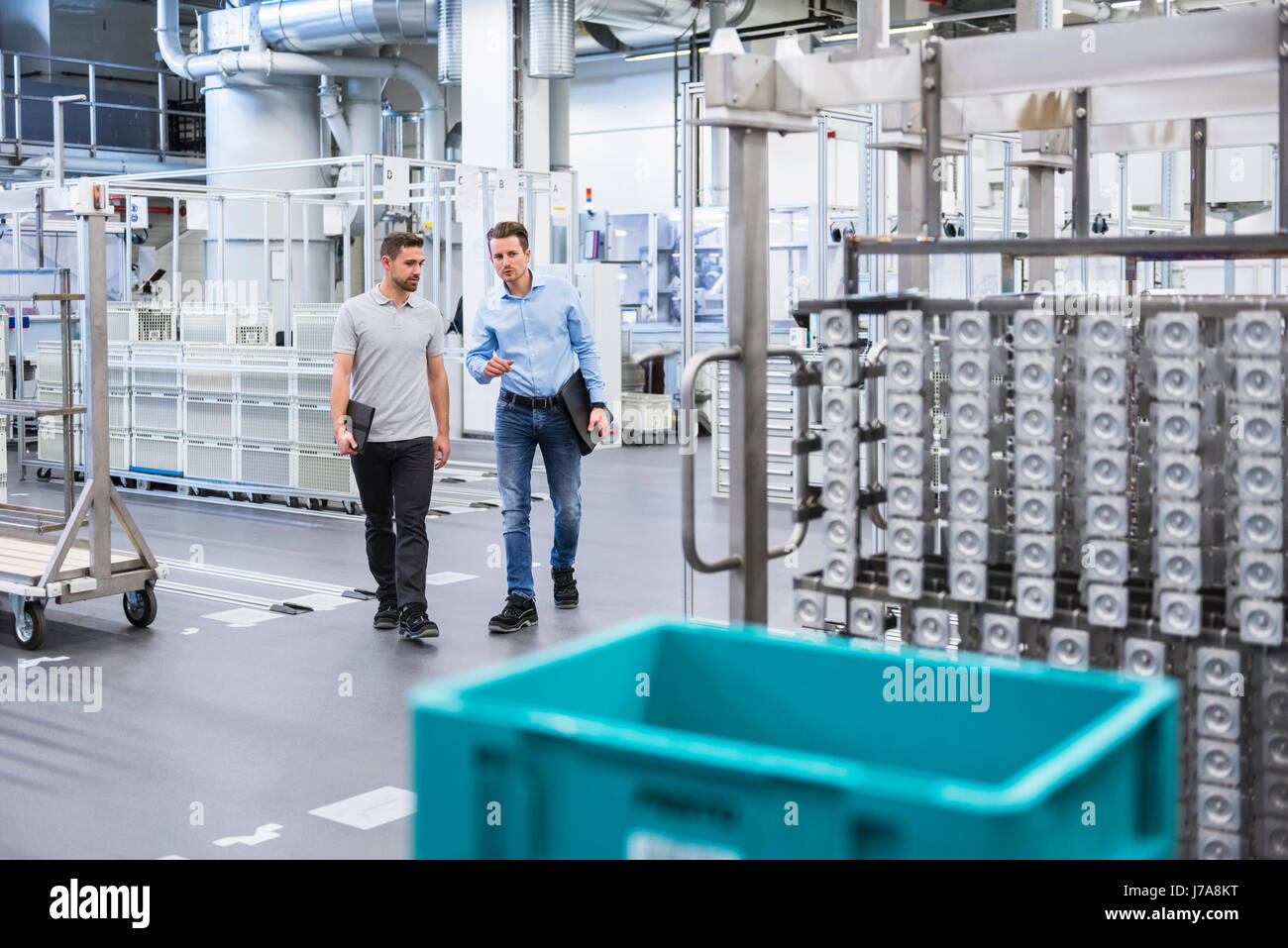 Two men walking and talking in factory shop floor Stock Photo - Alamy