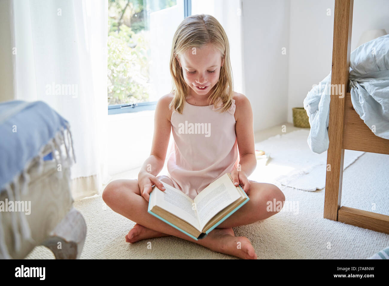 Little girl sitting on the floor at home reading a book Stock Photo - Alamy