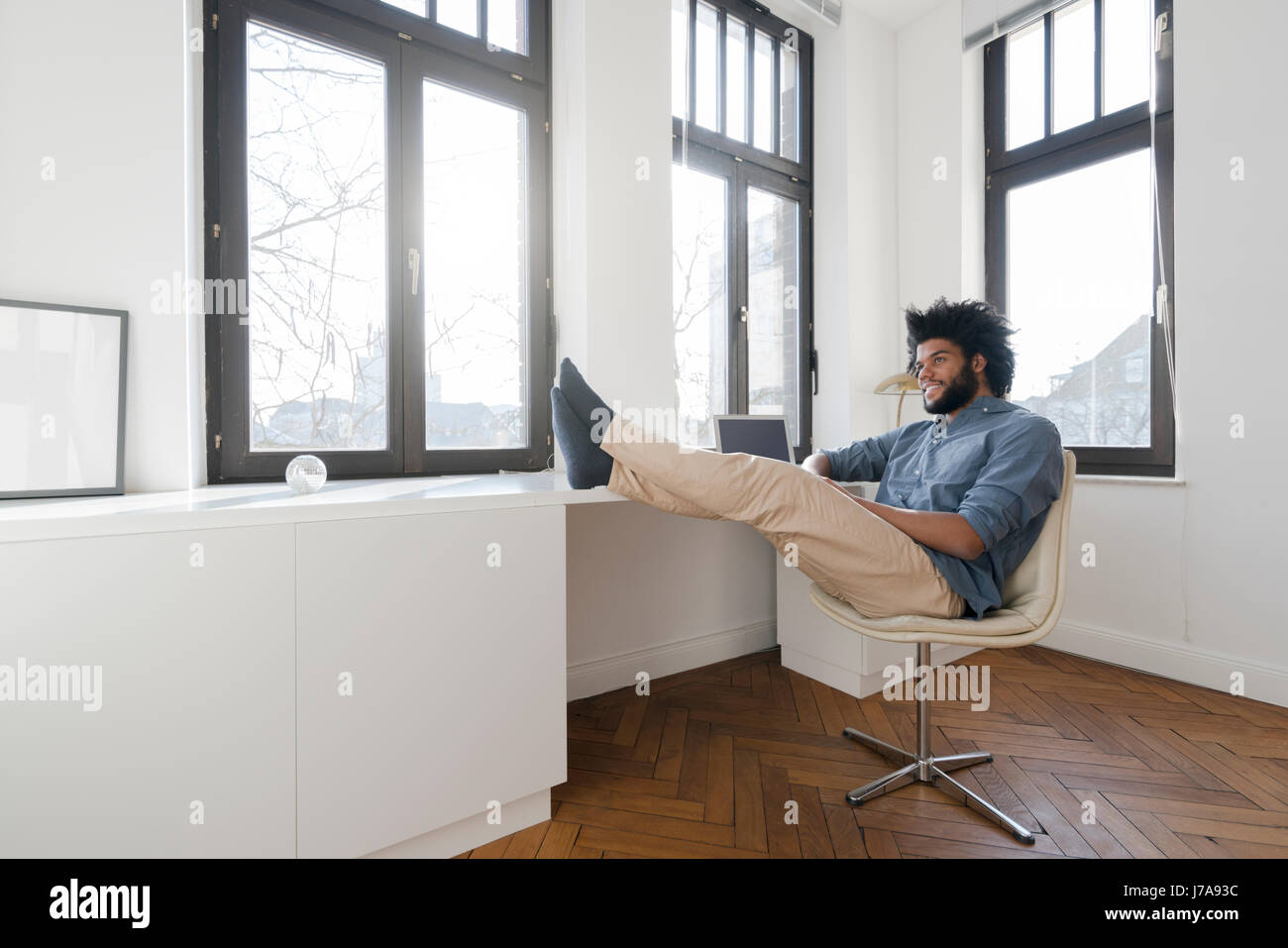 Man sitting in minimalist empty room on chair Stock Photo