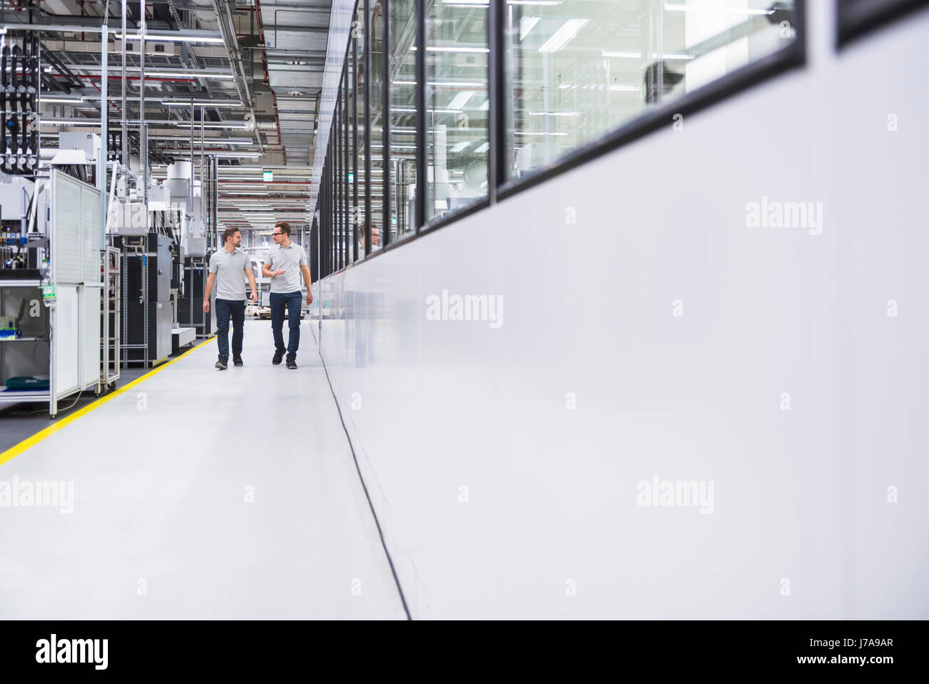 Two men walking and talking in factory shop floor Stock Photo - Alamy