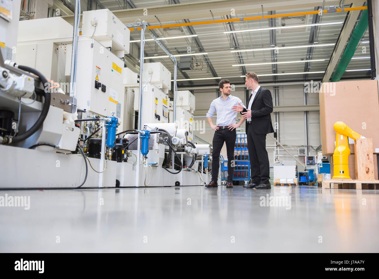 Two men talking in factory shop floor Stock Photo - Alamy