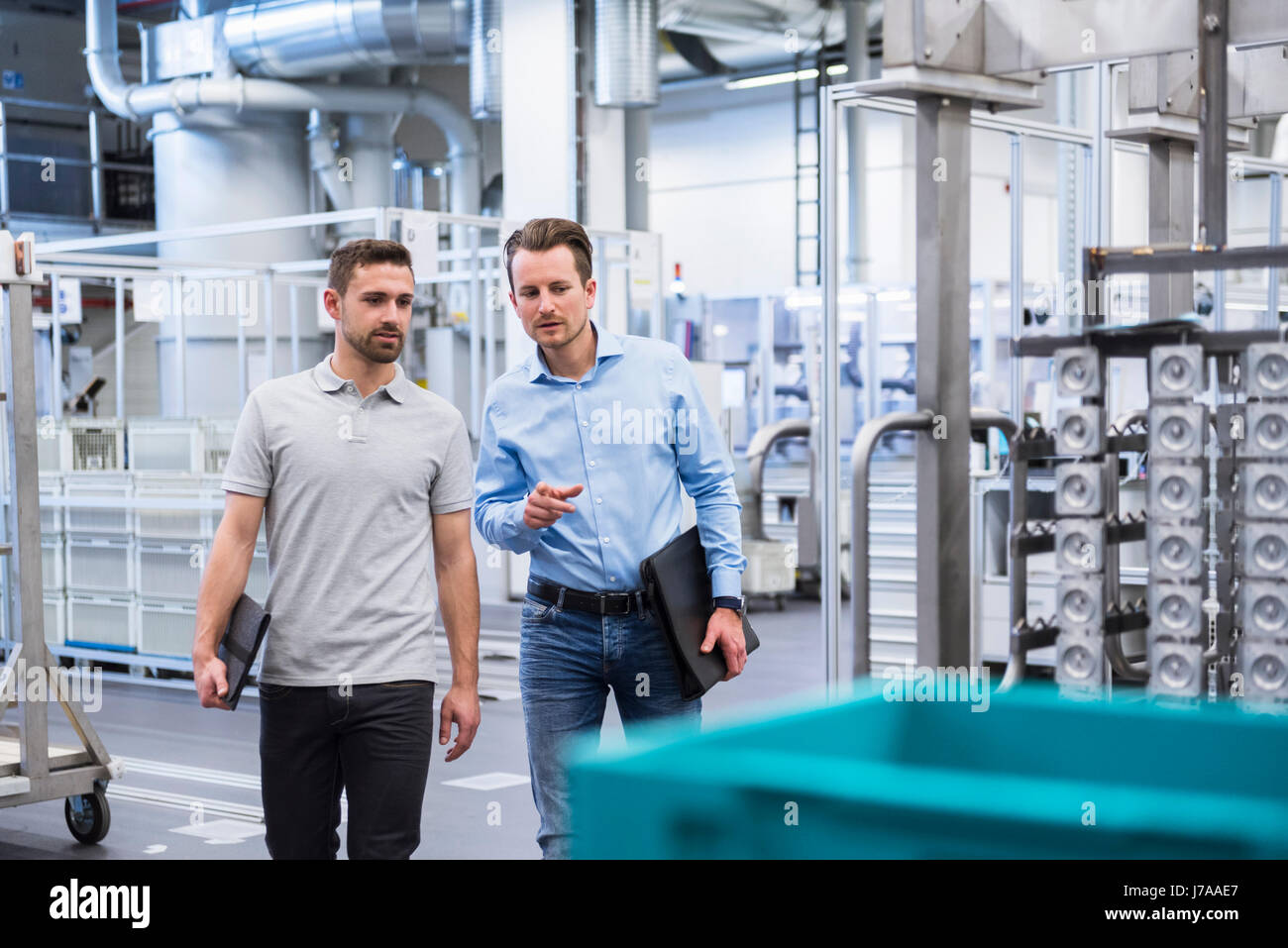 Two men walking and talking in factory shop floor Stock Photo - Alamy