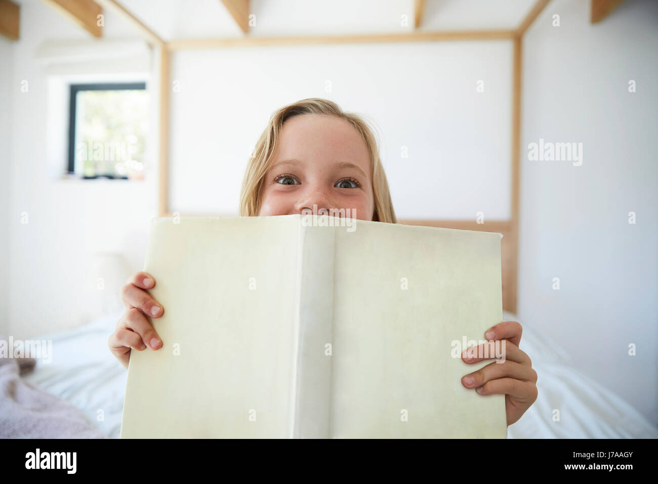 Portrait of little girl with book at home Stock Photo - Alamy