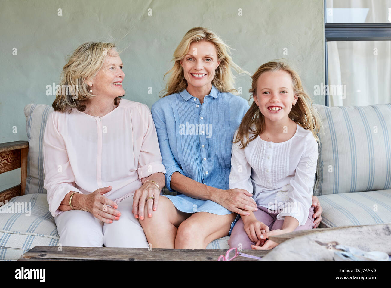 Little girl sitting together with grandmother and mother on terrace ...