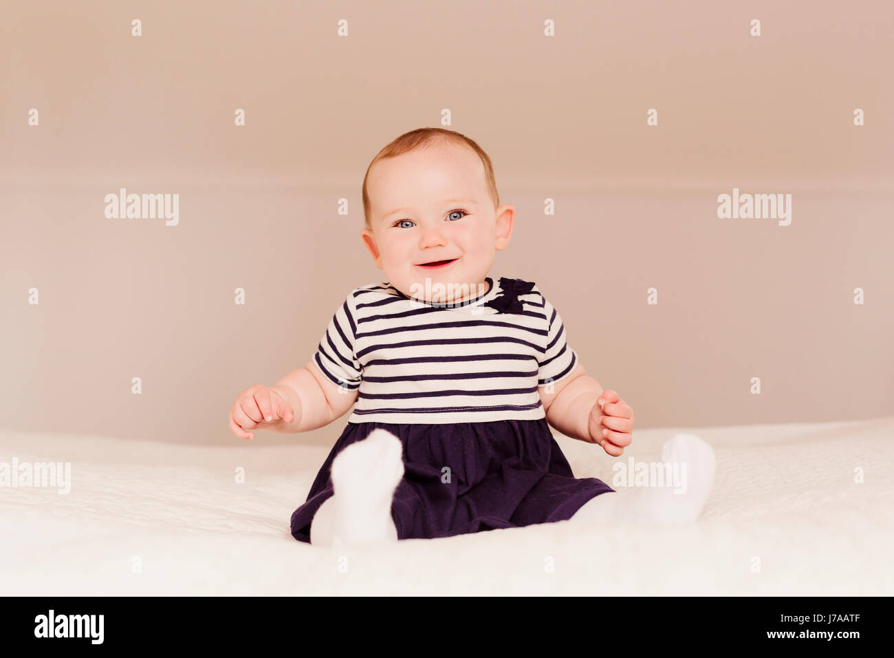 Portrait of smiling baby girl sitting on bed Stock Photo - Alamy