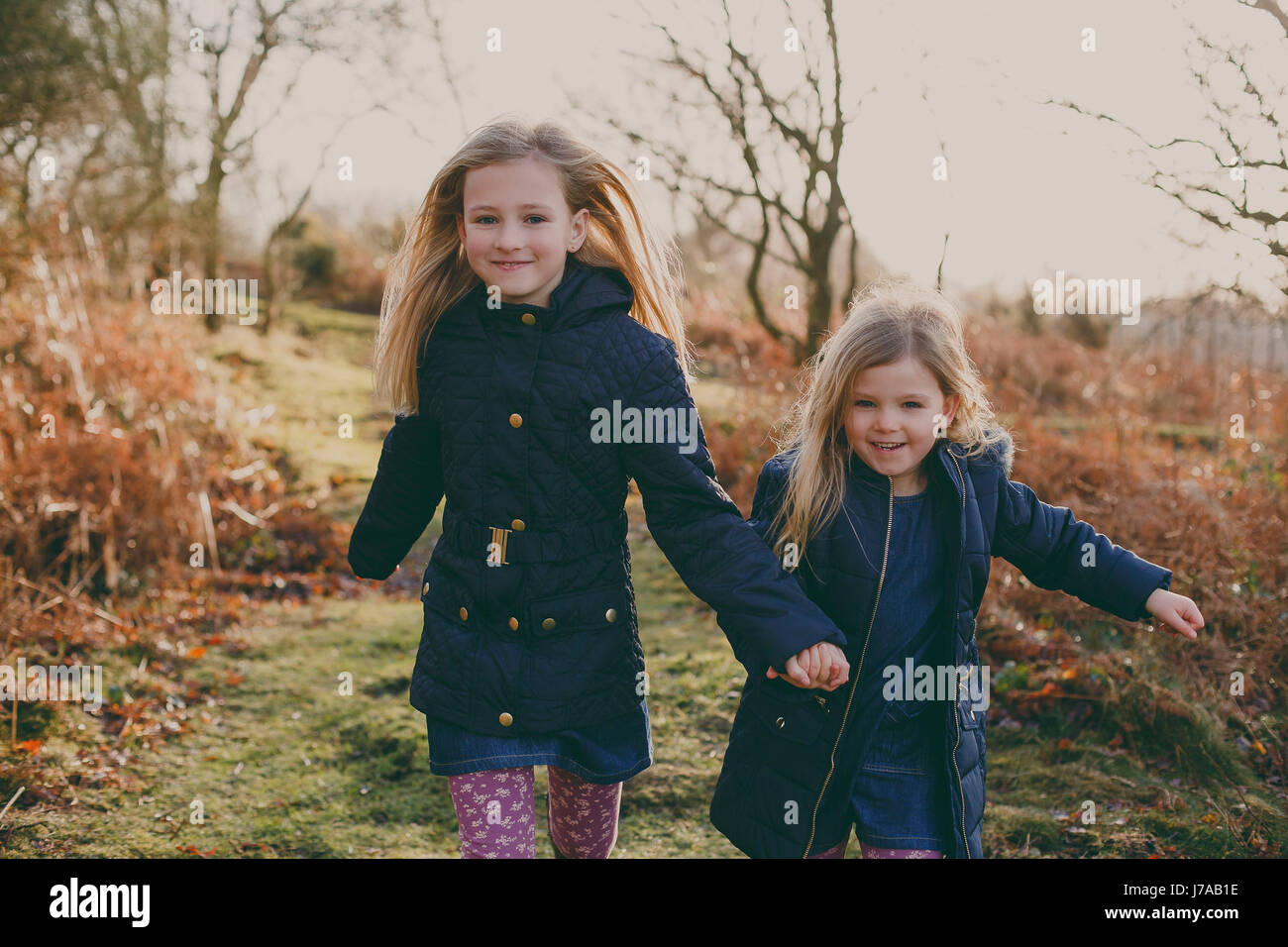 Two sisters running on a meadow together Stock Photo