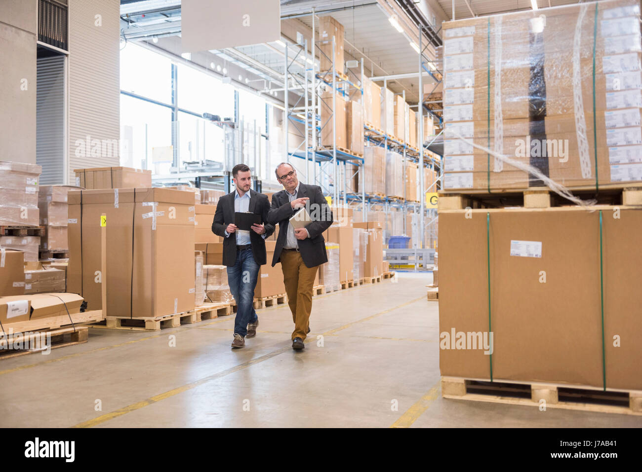 Two men walking in factory warehouse Stock Photo - Alamy