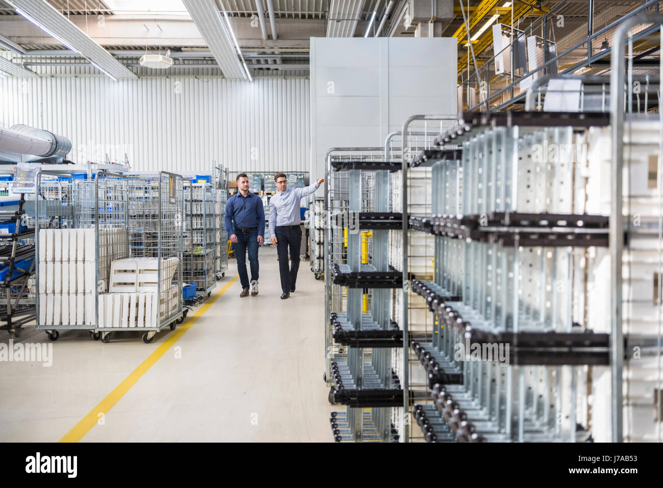 Two men walking and talking in factory shop floor Stock Photo - Alamy