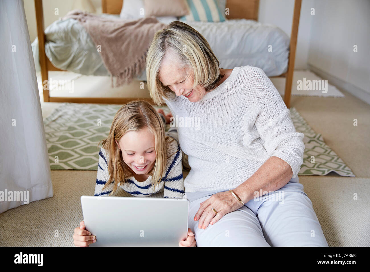 Little girl and her grandmother using tablet at home Stock Photo - Alamy