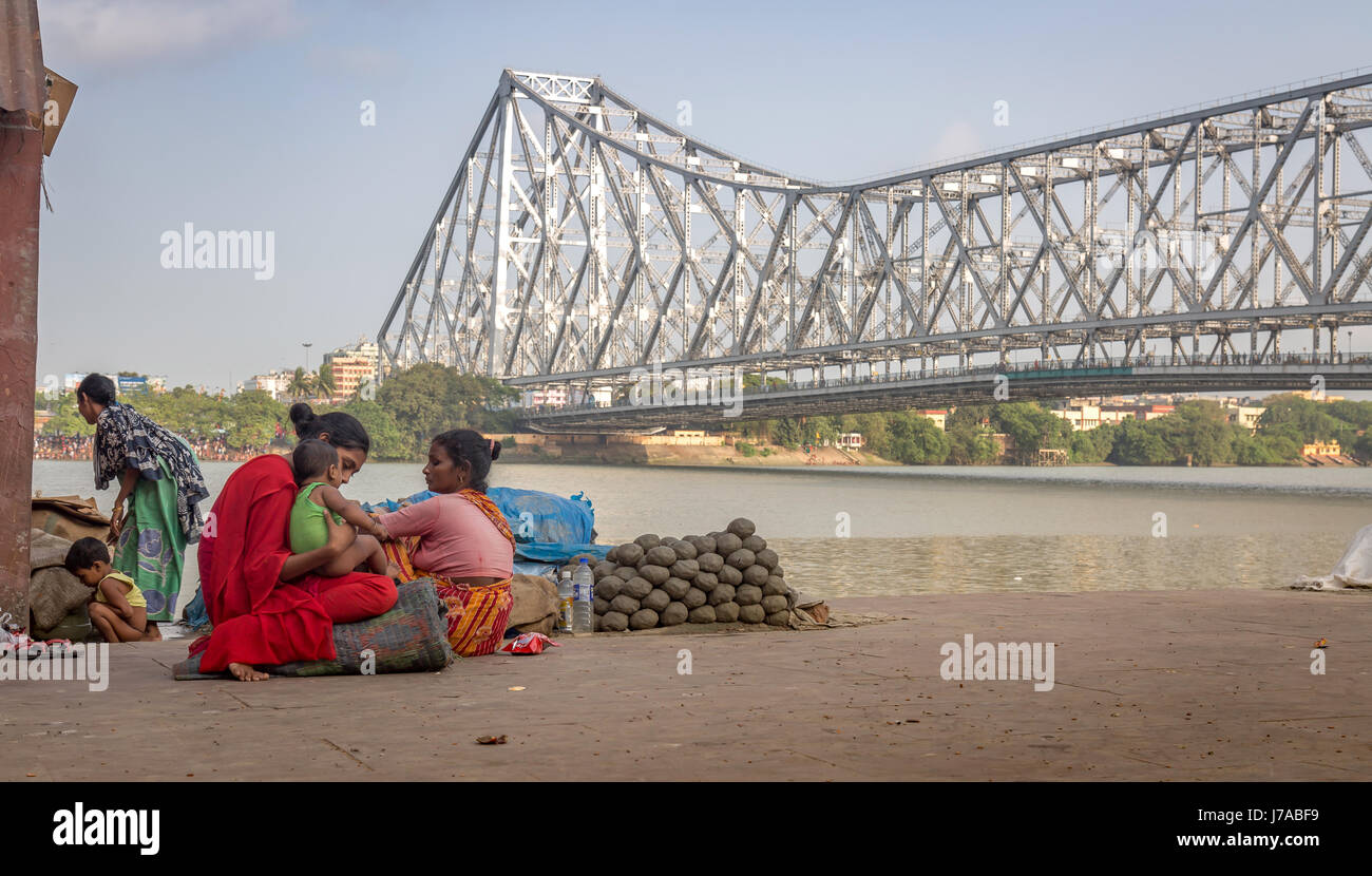 Happiness in poverty. A mother caresses her baby girl child at the Hooghly river banks near Howrah bridge at Kolkata, India. Stock Photo