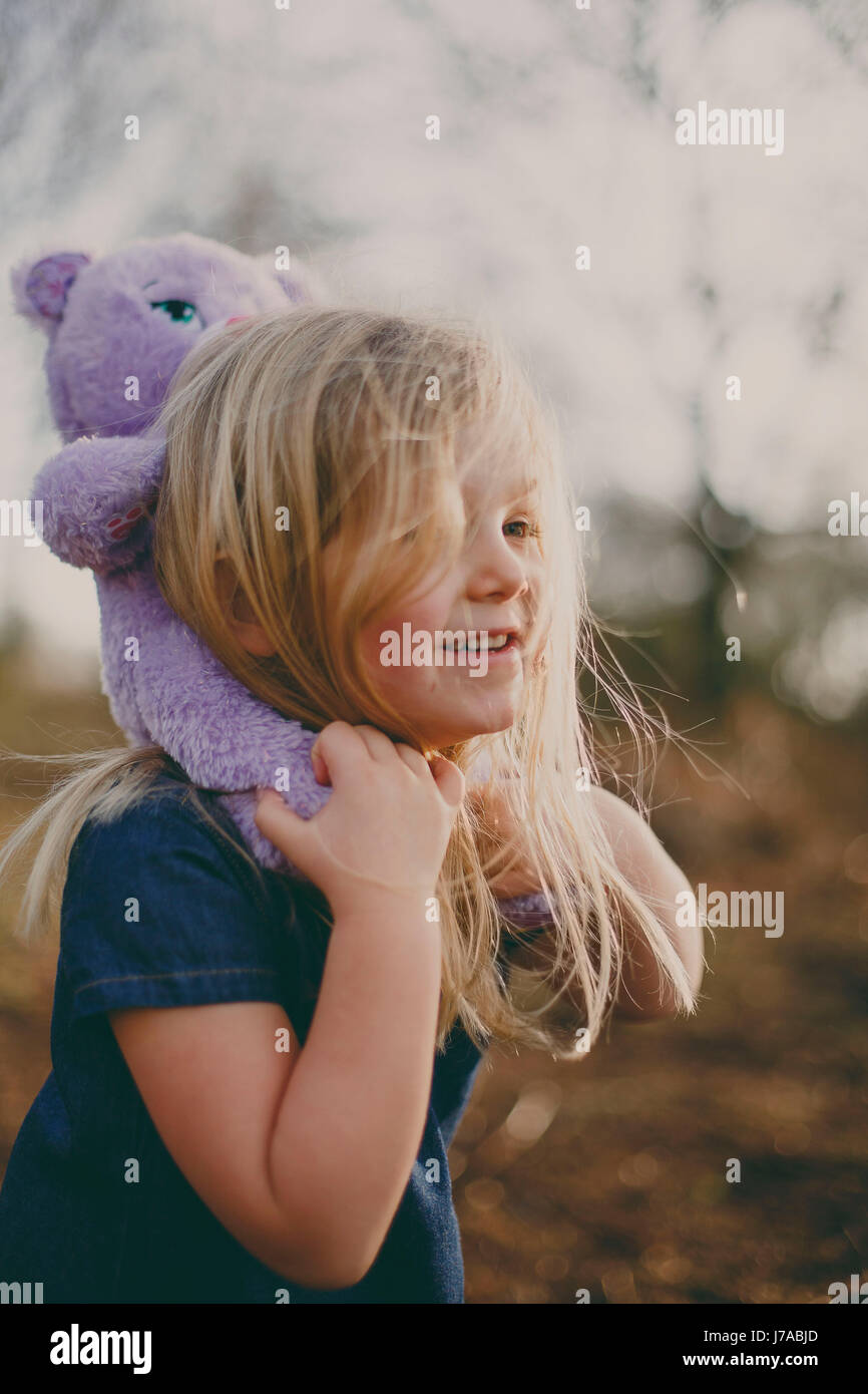 Smiling girl carrying a teddy outdoors Stock Photo