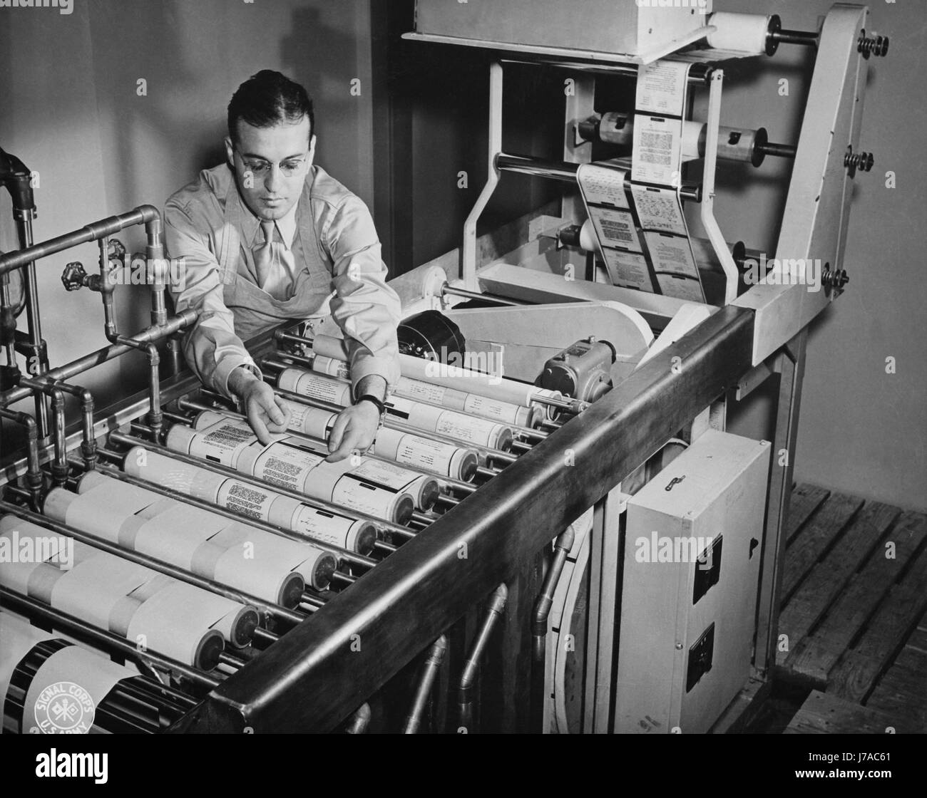 Paper reproductions from V-mail microfilm are developed on a paper processing machine, 1943. Stock Photo