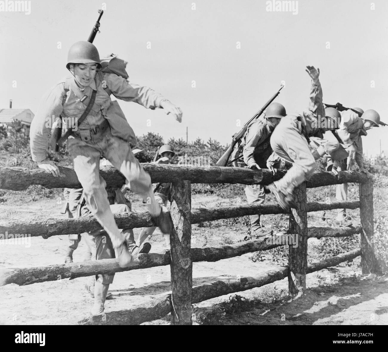 Soldiers climb over a rail fence at Camp Edwards, Massachusetts, circa 1942. Stock Photo