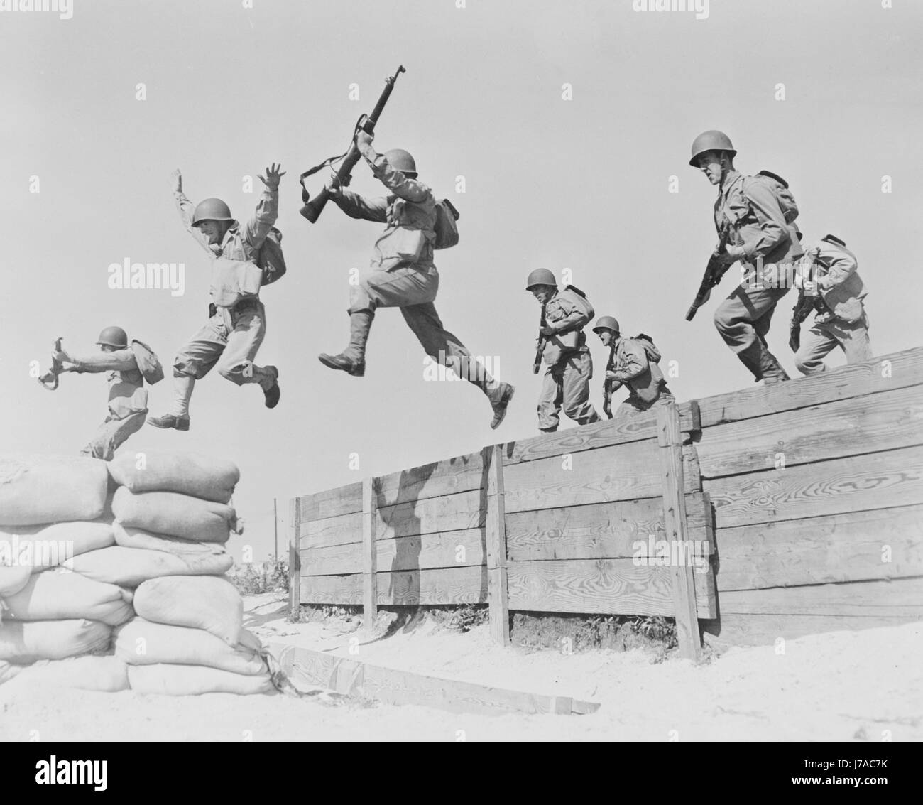 Artillerymen take a running leap over an obstacle at Camp Edwards