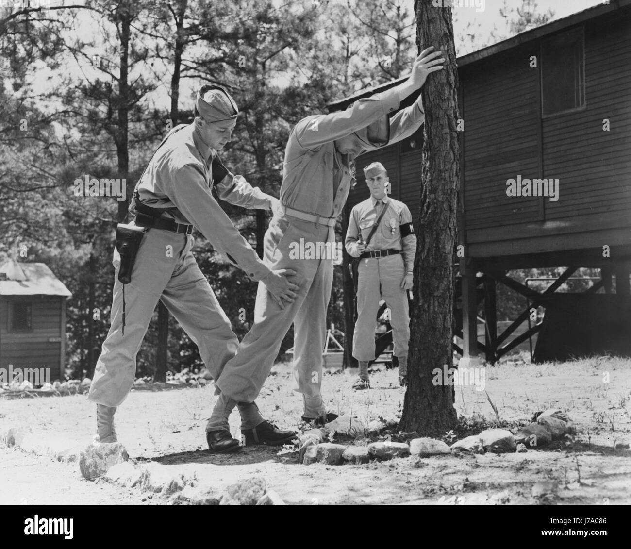 Military police search a man for concealed weapons, circa 1942. Stock Photo