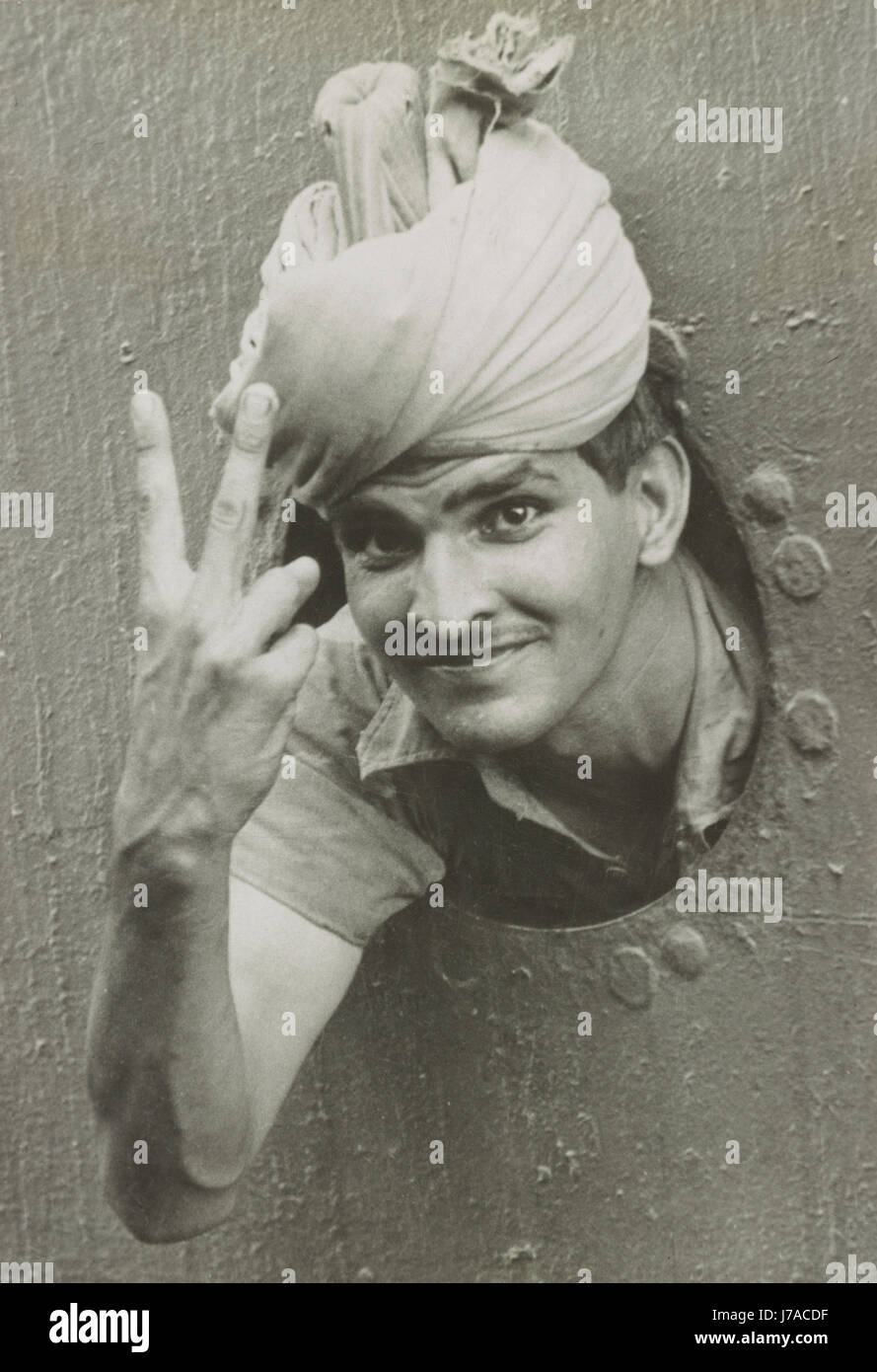 An Indian soldier gives the V sign from the port-hole of a ship, 1941. Stock Photo
