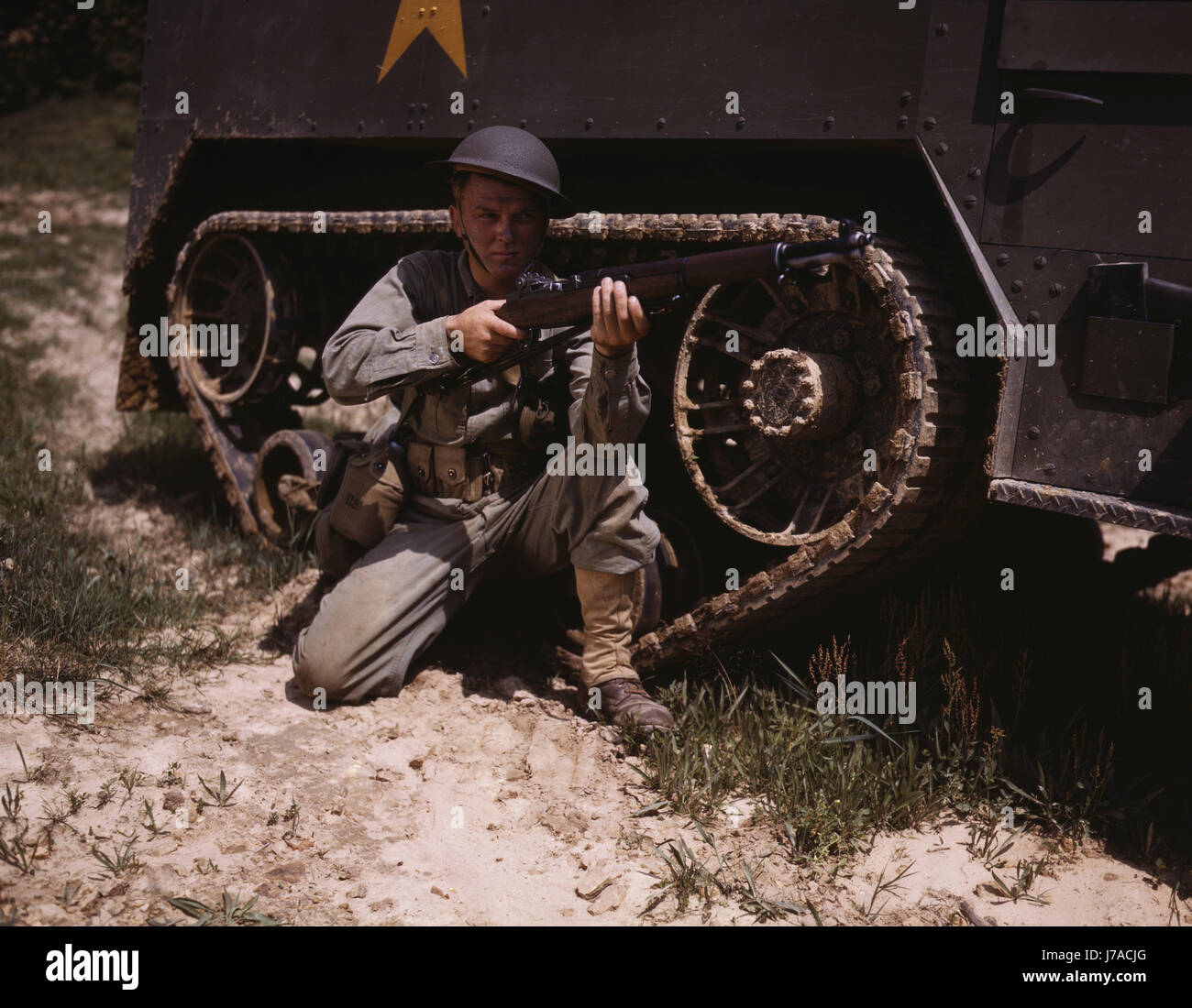 A soldier holds and sights his Garand rifle next to a half-track at Fort Knox, Kentucky. Stock Photo