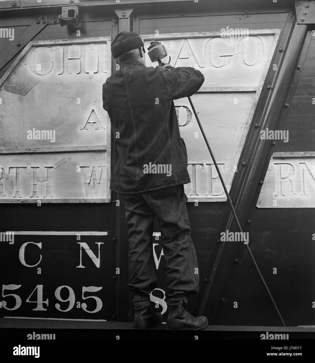 Worker stenciling the name of the railroad on newly painted freight cars. Stock Photo